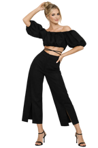 Woman wearing a black outfit with wide-leg pants and a top with puffed sleeves on a white background