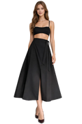 Woman wearing a black two-piece outfit with a skirt and top on a white background