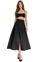 Woman wearing a black two-piece outfit with a skirt and top on a white background