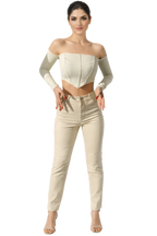 Woman wearing a white off-shoulder top and beige pants on a white background