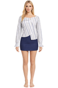 Woman wearing a striped shirt and navy skirt on a white background