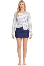 Woman wearing a striped shirt and navy skirt on a white background