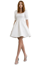 Woman wearing a white dress on a plain background
