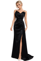 Woman wearing a black evening gown with a slit on a white background