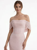 Woman wearing a pink off-shoulder gown on a white background