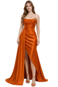 Woman wearing a strapless orange evening gown with a slit on a white background