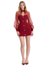 Woman wearing a red dress with sheer sleeves on a white background
