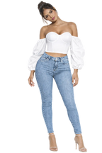 Woman wearing a white strapless top and light blue jeans on a white background
