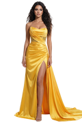 Woman wearing a yellow evening gown with a slit on a white background