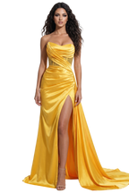 Woman wearing a yellow evening gown with a slit on a white background
